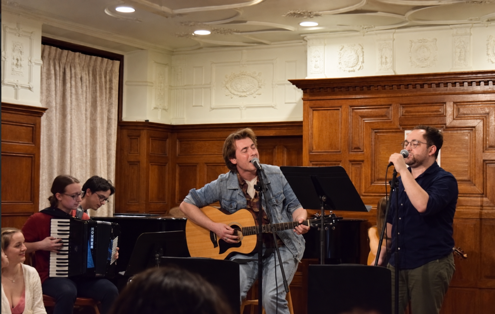 Tristan singing and playing acoustic guitar with fellow musicians