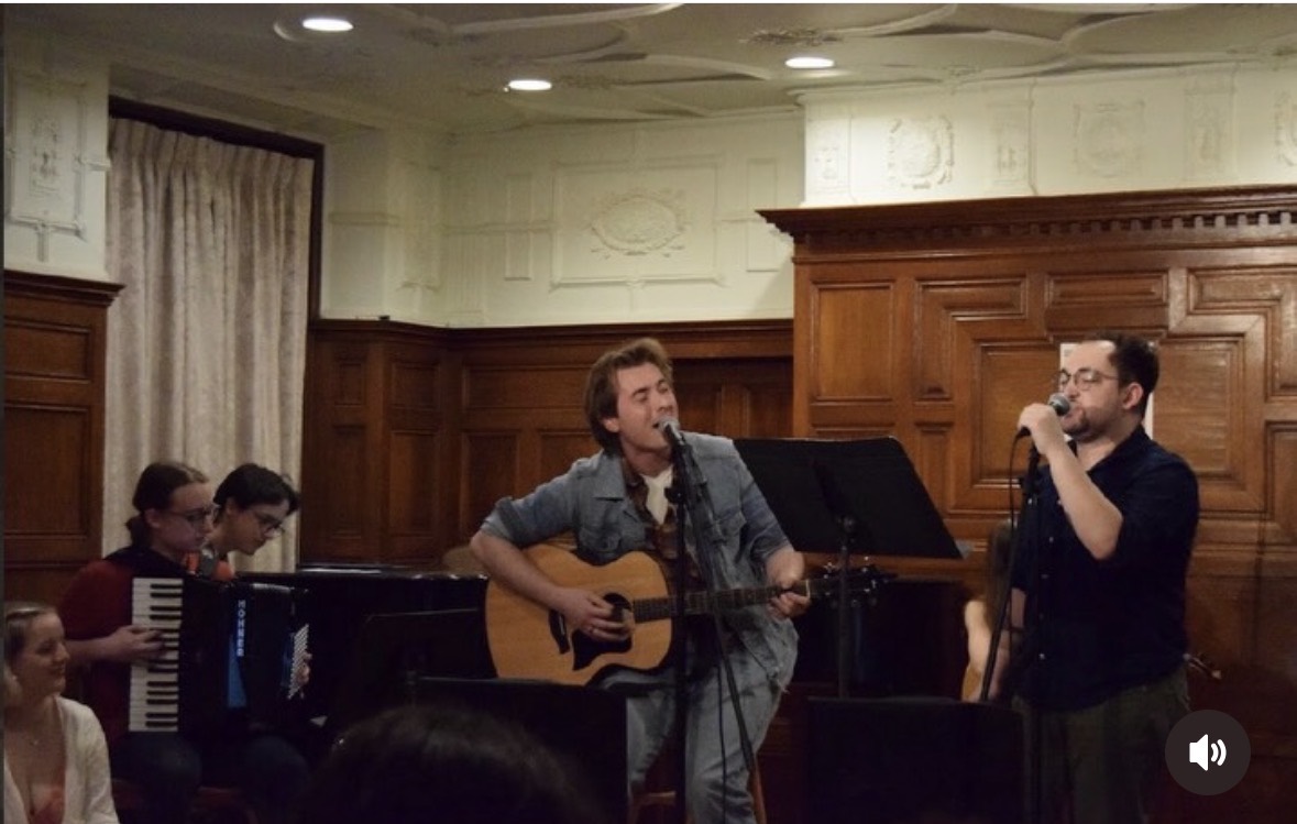 Tristan singing and playing acoustic guitar with fellow musicians